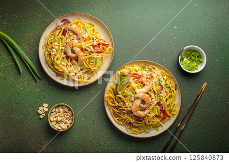Two plates of thai noodles with shrimp and peanuts on green background, dish of Thailand Two plates of thai noodles with shrimp and peanuts on green background, dish of Thailand 125840873