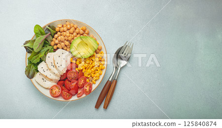 Healthy bowl with chicken breast, avocado, chickpeas, corn and tomatoes on grey background top view. Diet and healthy food concept 125840874