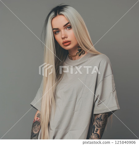 Beautiful blond with long hair in oversized T-shirt on grey. A trendy mockup with a tattoo, fashion image of modern and artistic product staging. Beautiful blond with long hair in oversized T-shirt on grey. A trendy mockup with a tattoo, fashion image of modern and artistic product staging. 125840906