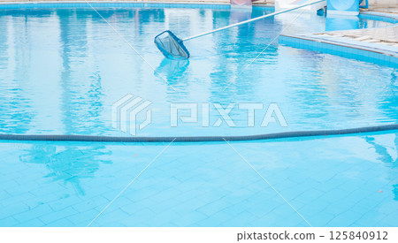 Man cleaning the swimming pool with vacuum cleaner. 125840912