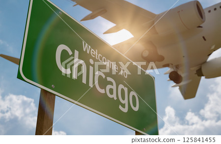 Welcome To Chicago Green Road Sign Against a Blue Sky and Clouds with Low Flying Airplane Above. 125841455