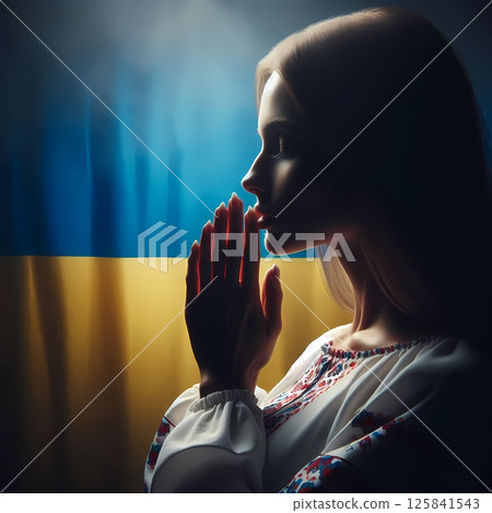 Woman praying in front of Ukrainian flag, traditional clothes, side profile 125841543