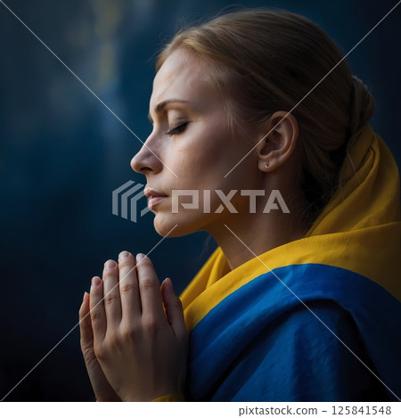 Woman praying in front of Ukrainian flag, traditional clothes, side profile 125841548