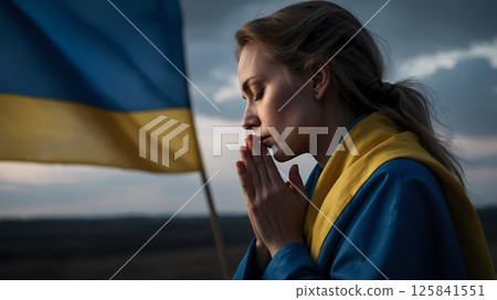 Woman praying in front of Ukrainian flag, traditional clothes, side profile 125841551