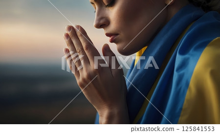 Woman praying in front of Ukrainian flag, traditional clothes, side profile 125841553