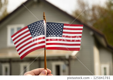 Two American flags in front of suburban house. American Independence Day patriotic decoration. Freedom and national pride in summer. Outdoors Two American flags in front of suburban house. American Independence Day patriotic decoration. Freedom and national pride in summer. Outdoors 125841781