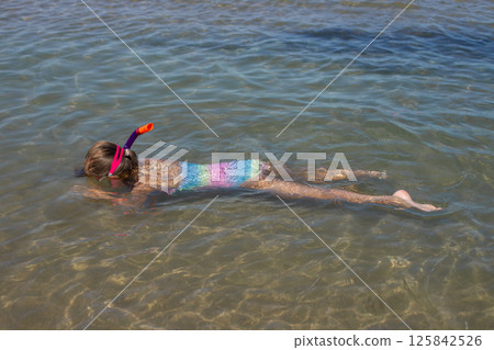 Young female child snorkeling in clear blue ocean water 125842526