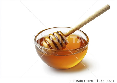 Small glass bowl of honey with wooden dipper isolated on white background with clipping path 125842883