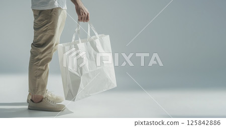 Man holding white paper shopping bag, copy space Man holding white paper shopping bag, copy space 125842886