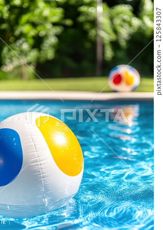Colorful beach balls floating in a refreshing clear blue swimming pool. 125843307