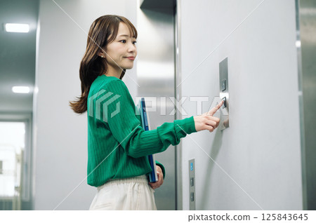A woman pushing the elevator button 125843645