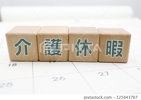 A wooden block with the words "Caregiver Leave" written on it is placed on a calendar 125843767