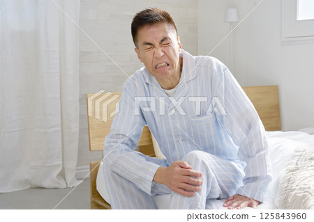 Middle-aged man in pajamas with knee pain 125843960