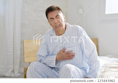 Middle-aged man in pajamas with chest pain 125843962