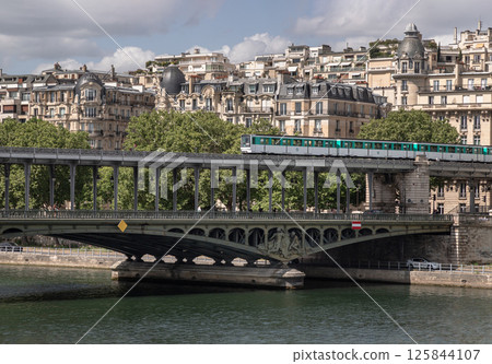 Stunning view of A metro train crossing the Pont de Bir Hakeim bridge with typical parisian buildings in the background. Stunning view of A metro train crossing the Pont de Bir Hakeim bridge with typical parisian buildings in the background. 125844107