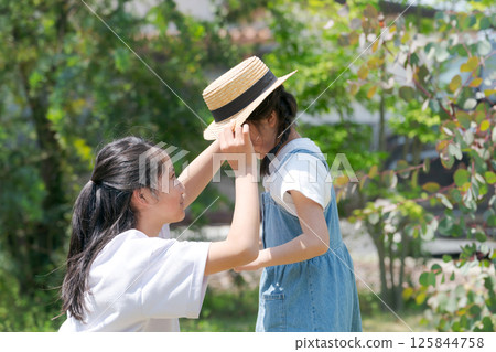 Older sister putting a hat on her younger sister 125844758