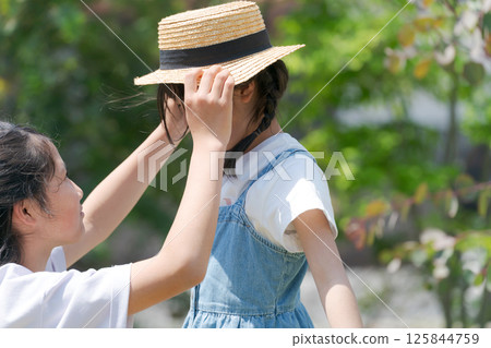 Older sister putting a hat on her younger sister 125844759