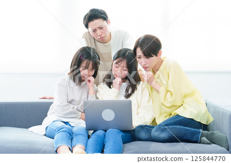 一家人正在使用電腦，臉上帶著憂慮的表情 125844770