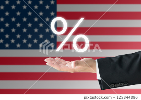 A man's hand in a suit holding up a percentage sign in front of the American flag - a tariff image A man's hand in a suit holding up a percentage sign in front of the American flag - a tariff image 125844886