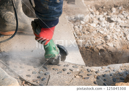 Construction worker cutting concrete with a disc grinder 125845308