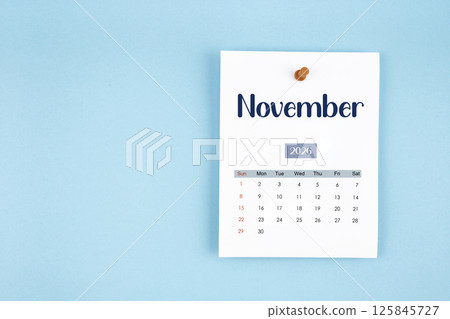 November 2026 calendar page with push pin on blue background. 125845727