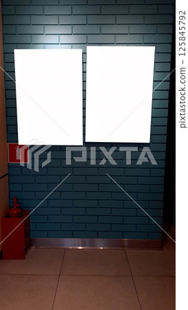 Blank billboards on teal tiled wall with fire extinguisher nearby 125845792