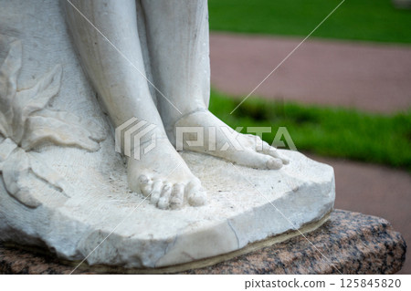 Close-up of marble sculpture feet in outdoor garden setting 125845820