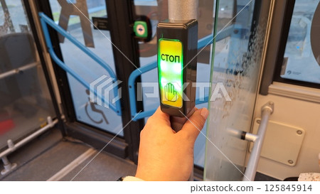 Moscow, Russia - April 26, 2025.Male hand pressing stop button on russian bus with accessibility features 125845914
