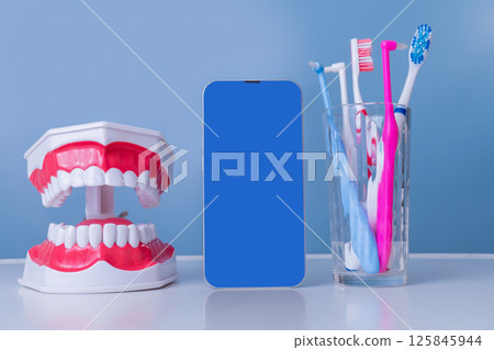 Dental hygiene tools and smartphone display on bathroom counter 125845944