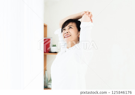  A woman stretching at the window side 125846176