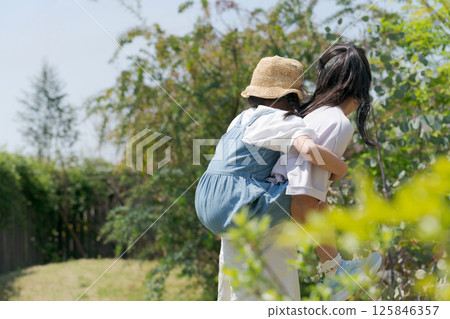 A girl carrying her younger sister on her back 125846357