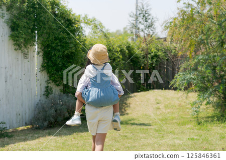 A girl carrying her younger sister on her back 125846361