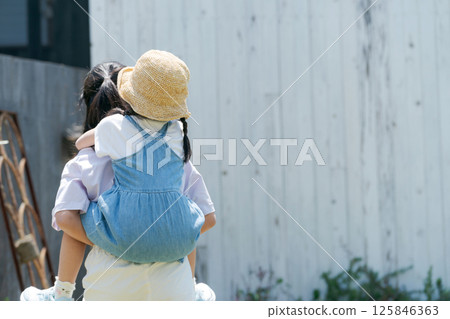 A girl carrying her younger sister on her back 125846363