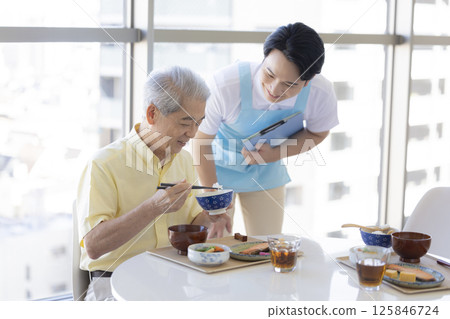 Care image: Senior man and caregiver eating 125846724
