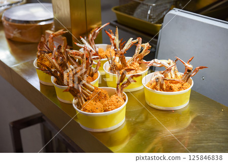Crispy fried crab claws served in yellow paper bowls at a Shanghai street food stall. Crunchy texture and golden coating ready to eat Crispy fried crab claws served in yellow paper bowls at a Shanghai street food stall. Crunchy texture and golden coating ready to eat 125846838