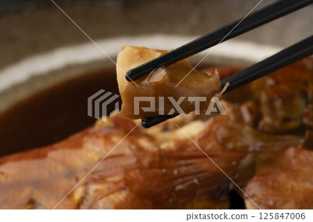 Lifting boiled red snapper with chopsticks 125847006