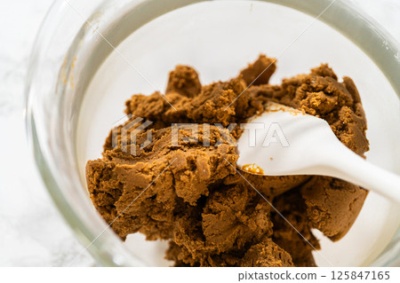 Final stage of mixing in the stand mixer, with the Spiced Gingerbread Cookie Dough Perfect for Baking fully combined and smooth, ready for shaping. The dough has a rich, dark color, ideal for holiday Final stage of mixing in the stand mixer, with the Spiced Gingerbread Cookie Dough Perfect for Baking fully combined and smooth, ready for shaping. The dough has a rich, dark color, ideal for holiday 125847165