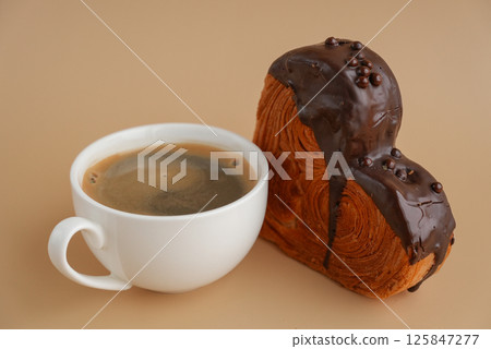 Coffee latte cappuccino drink beverage morning breakfast Heart shaped dark chocolate croissant on beige background with copy space. Puff pastry new trendy sweet dessert bakery. Creamy dough 125847277