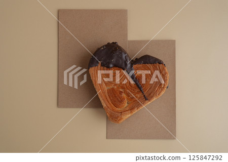 Delicious fresh croissant topped with Dark chocolate flavor Ganache. Creation unique heart shape bakery. Puff pastry holiday love gift present idea Valentine's day Delicious fresh croissant topped with Dark chocolate flavor Ganache. Creation unique heart shape bakery. Puff pastry holiday love gift present idea Valentine's day 125847292