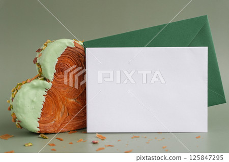 Empty template paper note with envelope greeting card mock up. Heart shaped pistachio croissant on green background with copy space. Puff pastry trendy sweet dessert bakery. Creamy dough experiment Empty template paper note with envelope greeting card mock up. Heart shaped pistachio croissant on green background with copy space. Puff pastry trendy sweet dessert bakery. Creamy dough experiment 125847295