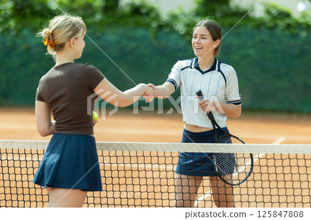 Young woman tennis player shaking hands with her opponent Young woman tennis player shaking hands with her opponent 125847808