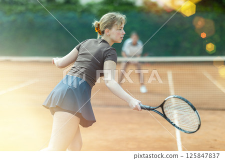 Girl plays tennis on open court with opponent 125847837
