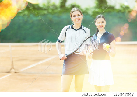 Adult and young women posing on tennis court 125847848