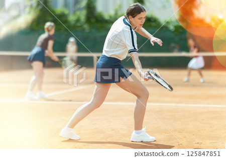Young woman playing doubles tennis on court Young woman playing doubles tennis on court 125847851