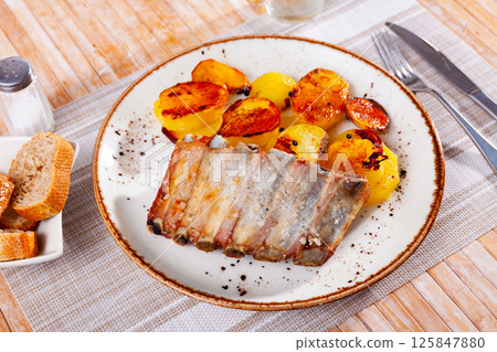 Fried pork ribs with side dish of baked potatoes Fried pork ribs with side dish of baked potatoes 125847880