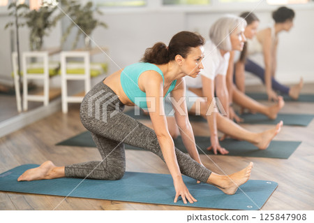 Group of women in activewear doing stretching exercises during training yoga in sports club Group of women in activewear doing stretching exercises during training yoga in sports club 125847908