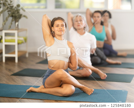 Lord of fishes - yoga pose practiced by group of women of different ages Lord of fishes - yoga pose practiced by group of women of different ages 125848180