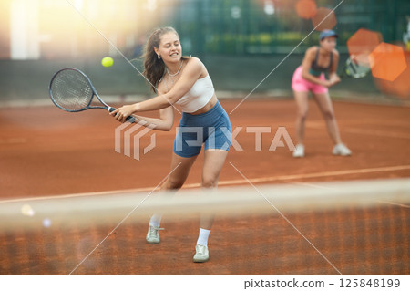Sporty young girl playing doubles tennis on outdoor court 125848199