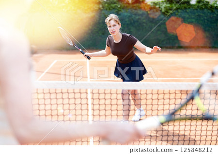 Young woman plays tennis on tennis court Young woman plays tennis on tennis court 125848212