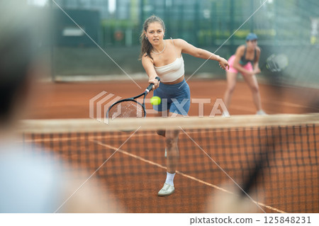 Sporty young girl playing doubles tennis on outdoor court Sporty young girl playing doubles tennis on outdoor court 125848231